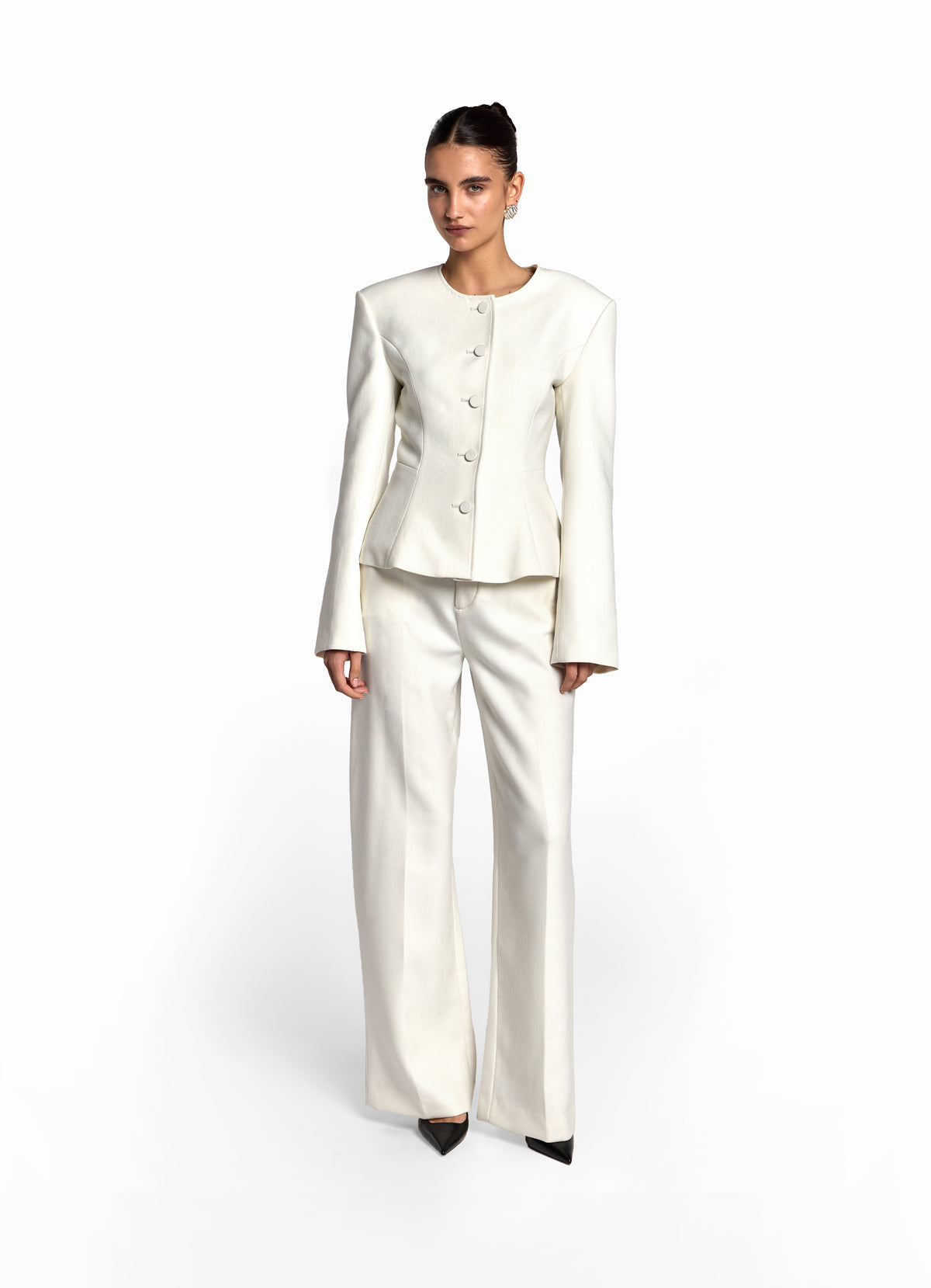 Front view of model wearing cream wool fitted jacket with matching cream wool trousers. 