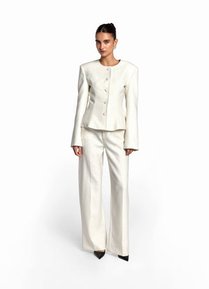Front view of model wearing cream wool fitted jacket with matching cream wool trousers. 