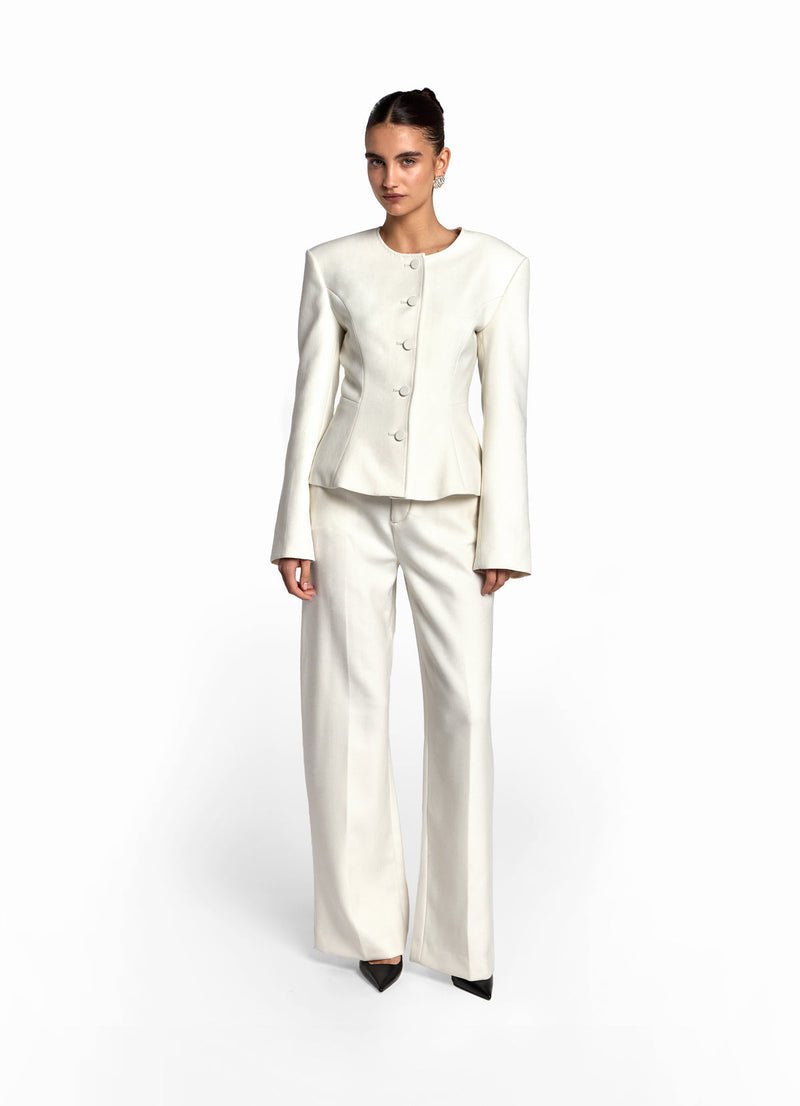 Front view of model wearing cream wool fitted jacket with matching cream wool trousers. 