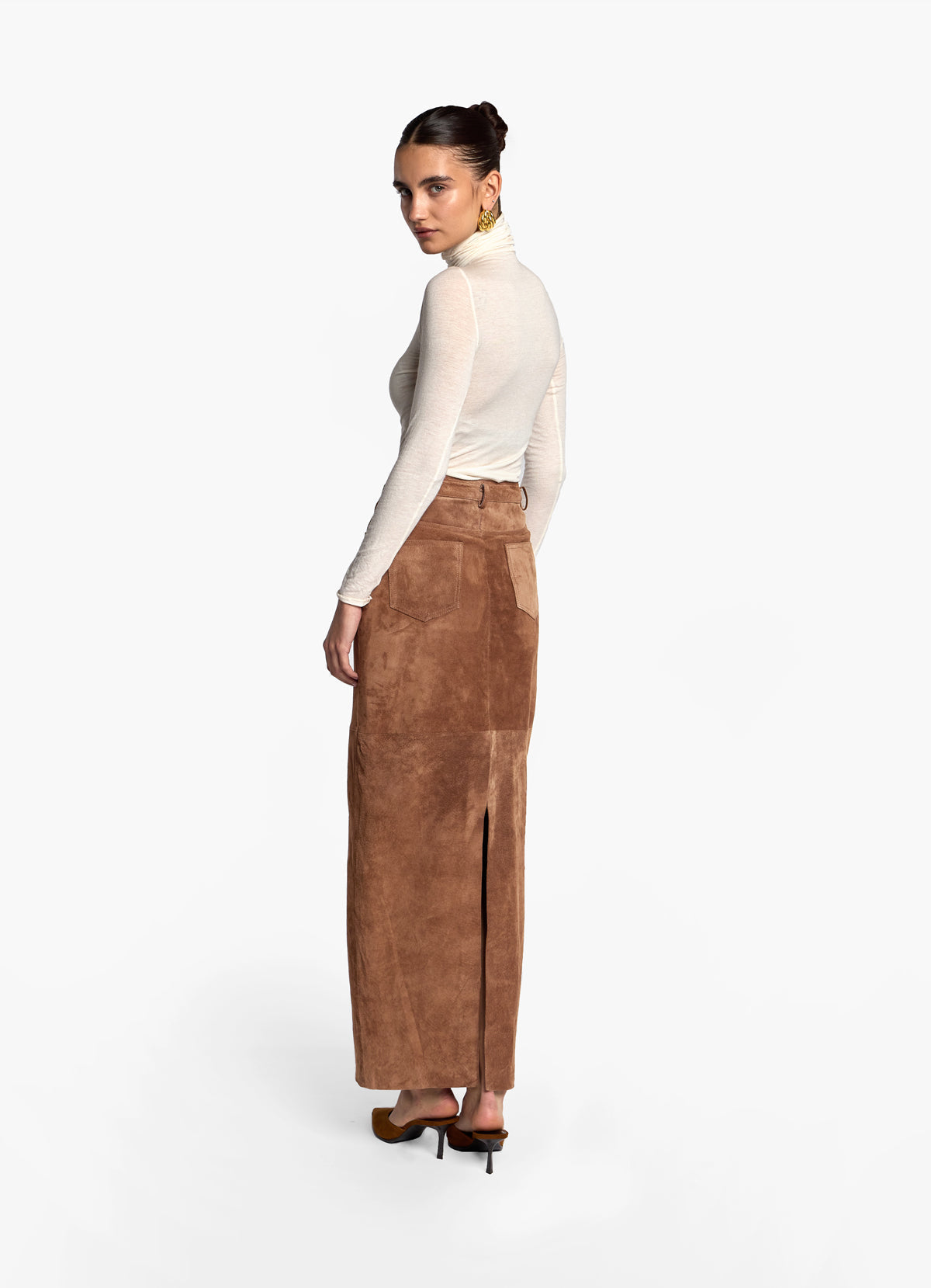 Back view of model wearing mocha suede maxi skirt showing back vent and pockets.