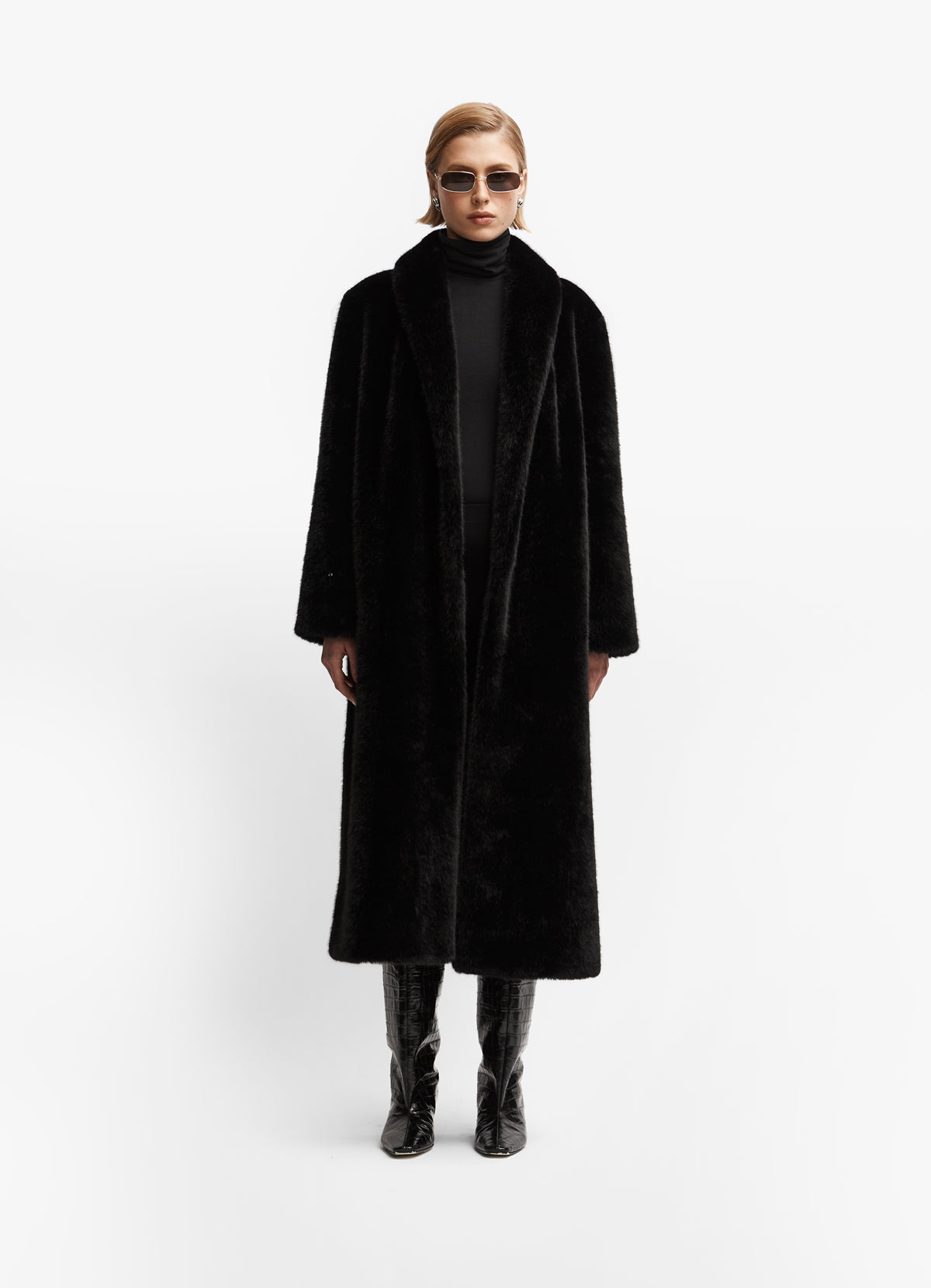 Model wearing black faux fur coat facing forward against white background.