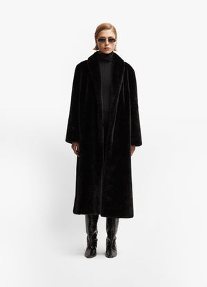 Model wearing black faux fur coat facing forward against white background.