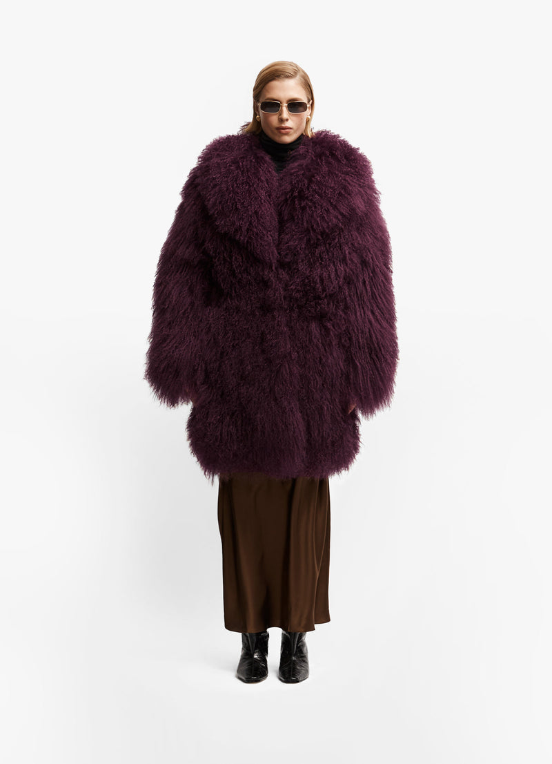 Model front facing wearing long length burgundy mongolian wool coat with collar.