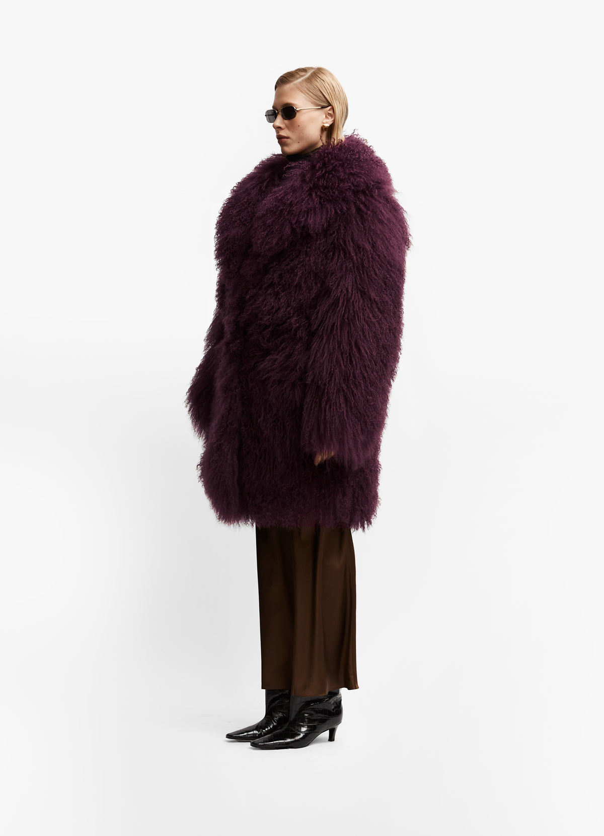 Side profile of model wearing longer burgundy mongolian wool coat with collar.