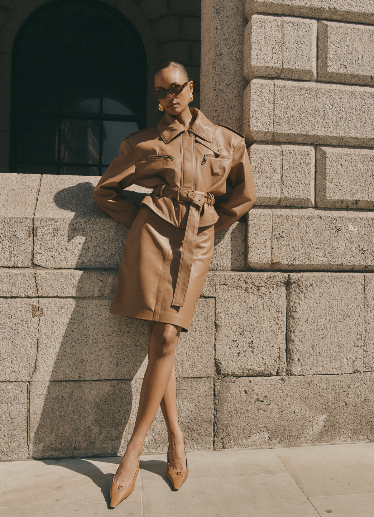 Model wearing mocha leather jacket paired with matching leather pencil skirt.